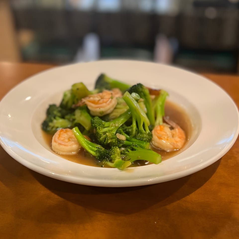 Thai Orchid's stir-fried broccoli and shrimp in a savory sauce, served on a white plate.
